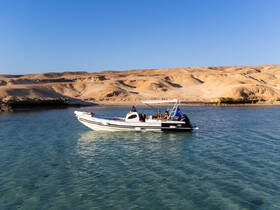 A scenic view of a boat navigating through clear waters, with stunning desert landscapes in the background — perfect for exploring remote coastal areas.