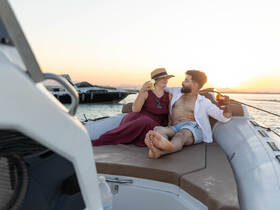 A couple enjoys cocktails on a boat at sunset, creating a perfect romantic atmosphere for special occasions or sunset cruises.