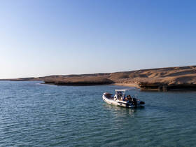 A scenic view of a boat navigating through calm waters, with a picturesque landscape in the background — perfect for exploring coastal destinations.