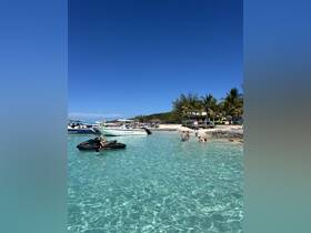 A lively beach scene featuring guests enjoying jet skiing and swimming in crystal-clear waters, perfect for a fun day in the sun.