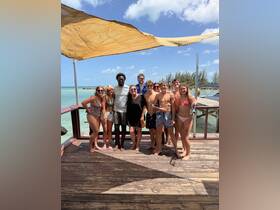 A cheerful group of friends poses together on a dock, enjoying a sunny day by the beach — perfect for memorable summer adventures.