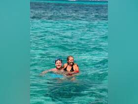 A joyful couple enjoys swimming in crystal-clear waters, perfect for snorkeling adventures and tropical getaways.