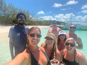 A cheerful group enjoys a sunny day at the beach, sipping cocktails and celebrating together — perfect for memorable outings and adventures.