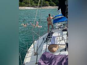 A lively group enjoys a fun day on the water, with some swimming and others relaxing on the yacht — perfect for a memorable celebration at sea.
