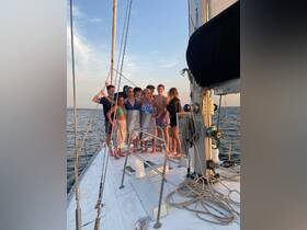 A lively group poses together on the deck of a yacht during sunset, capturing a memorable moment of celebration on the water.