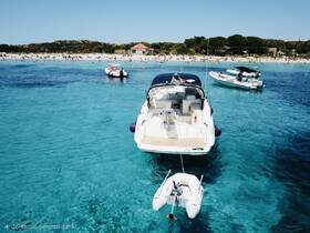 A stunning view of boats anchored near a vibrant beach, with people enjoying the clear turquoise waters — a perfect summer getaway.