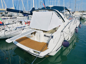 A stunning view of the back of a yacht named 'Mirea' docked in a marina, showcasing its elegant design and wooden deck.