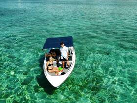 A couple enjoys a sunny day on a boat in crystal-clear waters, perfect for summer adventures and water activities.