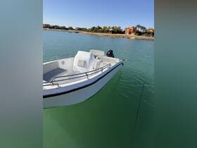 A sleek speedboat docked in calm waters, showcasing its modern design against a scenic backdrop of waterfront properties.