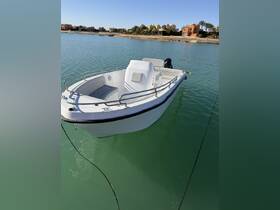 A sleek speedboat anchored in calm waters, showcasing its elegant design against a picturesque backdrop of coastal homes.