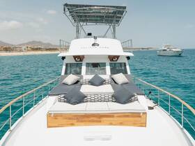 A stunning view of the deck of the Pelican Cabo yacht, featuring comfortable seating and a beautiful backdrop of the coastline, perfect for luxury cruising.