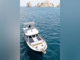 An aerial view of the 'Pelican' yacht anchored in clear blue waters, showcasing its elegant design against a backdrop of stunning rock formations.