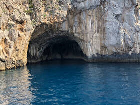 A stunning view of a coastal cave reflecting in the clear blue waters, perfect for exploring scenic destinations while boating.