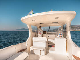 Inside view of a boat's helm area, featuring two individuals seated and ready for navigation, showcasing a comfortable and stylish cabin design.