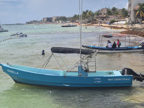 A vibrant blue boat named 'Isabella' is anchored near a beach, with people enjoying the water and the scenic shoreline in the background — a perfect setting for a day of fun on the water.