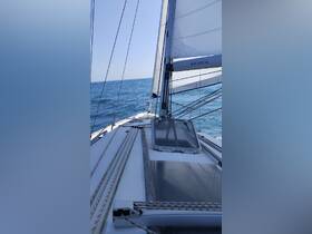 A close-up view of a Jeanneau sailboat underway, showcasing the sails and deck against a backdrop of clear blue waters.