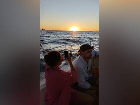 A couple captures a stunning sunset while aboard a yacht, creating unforgettable memories on the water.
