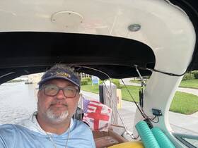A man poses inside the helm of a boat, showcasing the interior space and equipment, perfect for navigating the waterways.