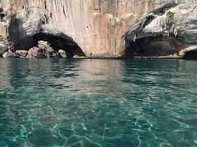 A stunning view of a rocky coastline with a cave, featuring crystal-clear waters — perfect for exploring and enjoying nature's beauty.