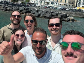 A cheerful group of friends poses for a selfie by the water, capturing a joyful moment during their boating adventure.