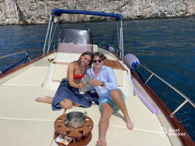 A couple enjoys a toast with cocktails on the deck of a yacht, surrounded by stunning coastal views — perfect for romantic getaways or special celebrations.
