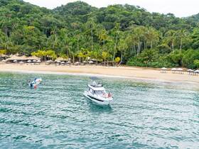 A scenic view of a boat near a beautiful tropical beach, showcasing the lush greenery and inviting shoreline — perfect for a relaxing getaway.