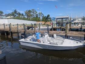 A person stands proudly on a Sea Pro boat at the dock, showcasing the vessel's features and inviting adventures on the water.