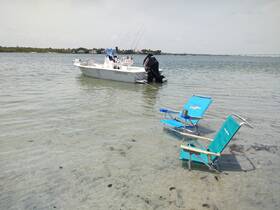 A fishing boat anchored in shallow waters with beach chairs set up nearby, creating a perfect spot for relaxation and enjoying the scenic views.