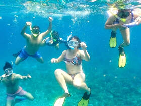 A lively group enjoys snorkeling underwater, showcasing the excitement of marine exploration in crystal-clear waters.