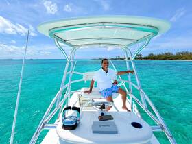 A smiling man enjoys the stunning turquoise waters aboard a boat, showcasing the perfect setting for a day of adventure on the water.