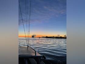 A serene sunset view from a boat, showcasing the tranquil waters and silhouettes of docked ships — perfect for evening cruises or peaceful reflections on the water.