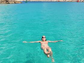 A woman enjoys a serene moment floating in the crystal-clear waters, perfect for relaxation and summer adventures.