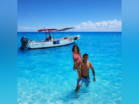 A joyful moment captured as a father carries his daughter in the crystal-clear waters, with a boat anchored nearby — perfect for family adventures and fun in the sun.