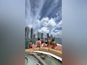 A lively group enjoys a day on a yacht in Miami, surrounded by stunning skyscrapers and vibrant skies — perfect for summer celebrations and fun on the water.