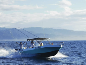 A lively fishing boat speeds through the ocean, with excited guests enjoying their time on the water — perfect for adventure seekers and fishing enthusiasts.