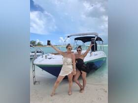 Two friends celebrate on the beach next to their boat, enjoying cocktails and a fun day in the sun — perfect for memorable outings and beach parties.