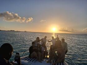 A lively group enjoys a sunset celebration aboard a boat, capturing memories against a stunning ocean backdrop — perfect for unforgettable gatherings on the water.