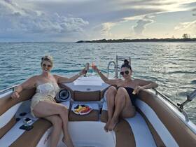 Two friends enjoy cocktails and fresh fruit on a boat, capturing the essence of a perfect day on the water with stunning views.