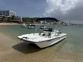 A sleek speedboat docked in shallow waters, showcasing its design against a scenic backdrop of palm trees and buildings — perfect for day trips and water adventures.