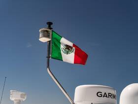 The Mexican flag proudly waves atop a boat, showcasing a vibrant maritime scene against a clear blue sky.
