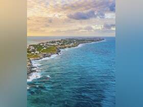 A stunning aerial view of a picturesque coastline, showcasing lush greenery and vibrant waters — a perfect representation of tropical paradise.
