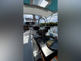 An interior view of a sailboat's helm area, showcasing the steering mechanism and a dining setup with snacks — perfect for enjoying meals while cruising.