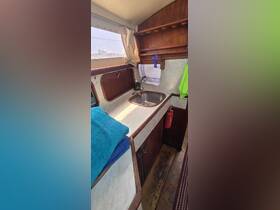 A cozy interior view of a boat's kitchen area featuring a sink, towels, and wooden cabinetry, perfect for meal prep while on the water.