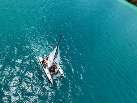 Aerial view of a lively group enjoying a catamaran sailing adventure in vibrant turquoise waters, perfect for unforgettable experiences on the water.
