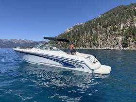 A man enjoys a sunny day on a sleek boat at the lake, surrounded by stunning mountain scenery — perfect for summer adventures on the water.