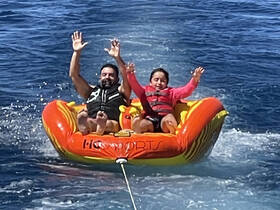 A thrilling moment as a man and a child enjoy tubing on the water, showcasing the excitement of family water sports adventures.