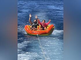 A thrilling moment as a man and a young girl enjoy tubing on the water, showcasing family fun and adventure during their boating experience.