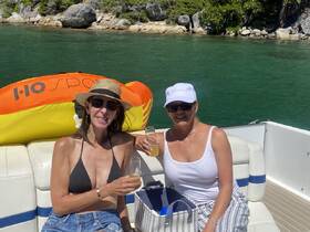 Two friends enjoy cocktails on a sunny day aboard a pontoon boat, perfect for celebrating special moments on the water.