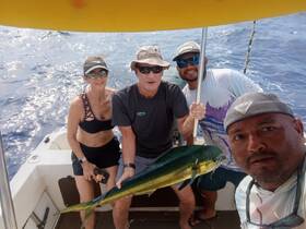 A group of friends proudly displays their catch while fishing on a boat, capturing the excitement of a successful day on the water.