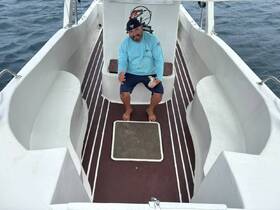 A man sits inside the cabin of a boat, showcasing the comfortable seating area — perfect for relaxing during a day on the water.
